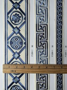 a ruler is next to some blue and white striped fabric with an intricate design on it