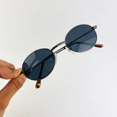 These round oval sunglasses are your everyday classic frames. Featuring a silver metal frame with black smoke lens. This style is unisex. True genuine vintage sunglasses from the 90s.  - 400 uv  Measurements: Lens height: 37mm Lens width: 51mm Bridge: 22mm Arm temple: 140mm Frame width: 133mm - new vintage from the 90s - includes sunglasses pouch Sunglasses 90s, 90s Sunglasses, Sunglasses Pouch, Bronze Metal, Metal Sunglasses, Rectangle Sunglasses, Oval Sunglasses, Classic Frame, Sunglasses Vintage