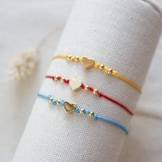 three bracelets with hearts on them sitting on top of a white cloth napkin holder