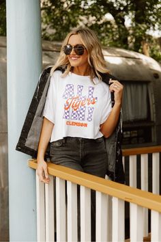 a woman leaning against a rail wearing a t - shirt with the word lsu on it