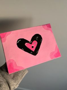 a person holding up a piece of art with a heart painted on it's side