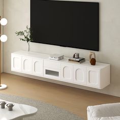 a flat screen tv mounted to the side of a white wall in a living room