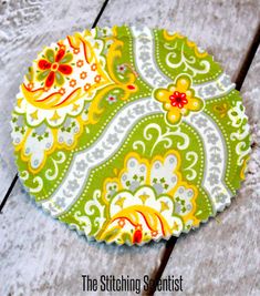 a green and yellow coaster sitting on top of a wooden table