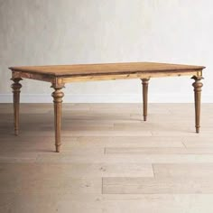 an old wooden table sitting on top of a hard wood floor next to a white wall