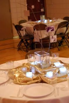 the table is set with white and gold plates, silver napkins, and candles