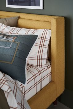 a bed with two pillows on top of it next to a framed picture above the headboard