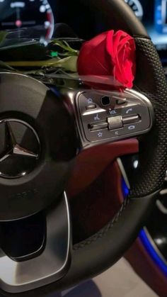 a red rose sitting on the steering wheel of a mercedes benz car with dashboard lights and gauges