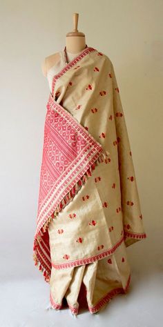 "This is hundred percent authentic Muga Silk Saree . It has Muga silk in the warp and weft . The interwoven motif yarns are in Guna ( golden zari ) and Acrylic. The design is traditional and known as Gamkharu and one of the most iconic designs of the region. The red and Muga combination is the classic combination that was always part of the bridal trousseau. Muga Silk - The most valued silk from India. Almost exclusively reared and produced in Assam, India. It is indigenous to the Brahmaputra Va Bohemian Tussar Silk Dupatta With Zari Weaving, Traditional Raw Silk Shawl With Traditional Patterns, Festive Woven Motifs Dupatta Shawl, Traditional Festive Shawl With Woven Motifs, Traditional Beige Tussar Silk Dupatta, Folk Style Dupatta With Traditional Drape And Motifs, Bohemian Traditional Wear With Weaving Work In Silk, Bohemian Traditional Silk Wear With Weaving Work, Bohemian Silk Saree With Weaving Work