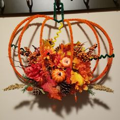 an arrangement of flowers and leaves hangs on the wall