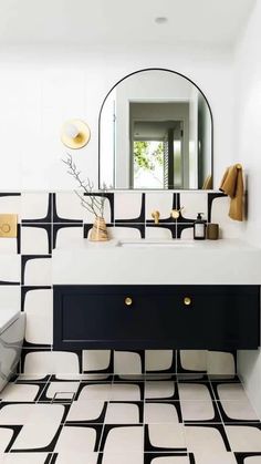 a bathroom with black and white tiles on the floor, sink, mirror and bathtub