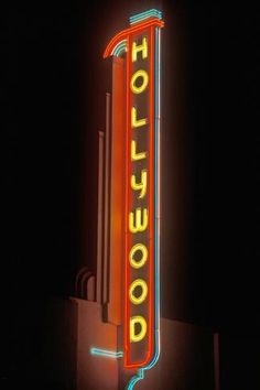 a neon sign that says hollywood on the side of a building at night with lights