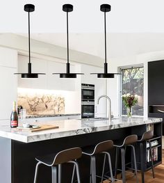 a kitchen with an island and bar stools next to the counter top in front of it