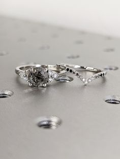 two wedding rings sitting on top of each other with drops of water in the background