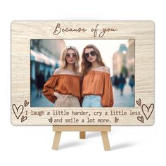 two women standing next to each other in front of a wooden easel with the words because