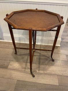 an octagonal wooden table sitting on top of a hard wood floor next to a white wall