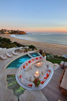 an outdoor hot tub next to the beach at dusk with candles lit up on it