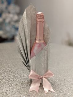 a bottle of champagne in a bag with a pink bow on the front and side