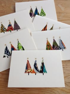 six cards with colorful christmas trees on them sitting on top of a wooden table next to each other