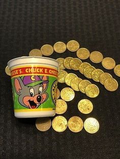 a cup filled with lots of gold coins next to a pile of little mouses