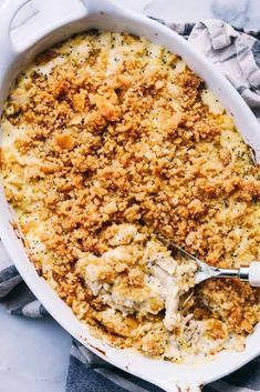 a white casserole dish filled with chicken and bread crumbled on top