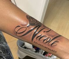 a person with a tattoo on their arm and the word name nicole written in cursive writing