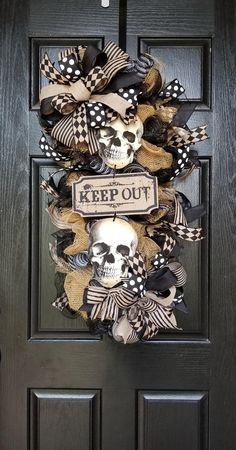 a black door with a skull wreath on it and a keep out sign hanging from the front