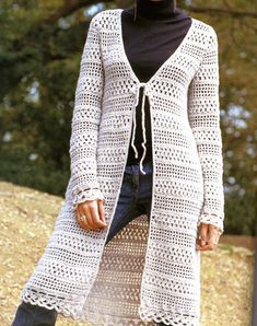 a woman is wearing a white crocheted cardigan and black turtle neck sweater