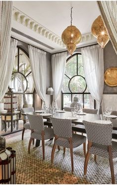 the dining room is decorated in gray and white with chandeliers hanging from the ceiling