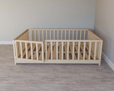 a wooden crib in a room with hard wood flooring and gray wall paint