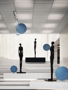 three statues are standing in the middle of a room with blue balls hanging from the ceiling