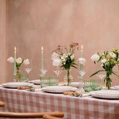 the table is set with plates and glasses, flowers in vases, and candles