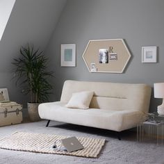 a white couch sitting on top of a rug in a living room next to a lamp