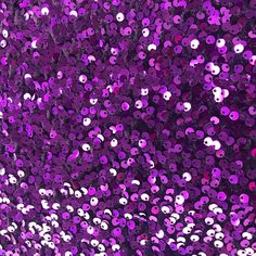 purple sequins are scattered over a black background