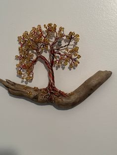 a tree made out of beads on a piece of wood with a hand holding it