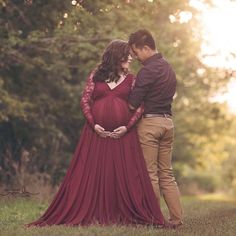 a pregnant woman in a red dress standing next to a man