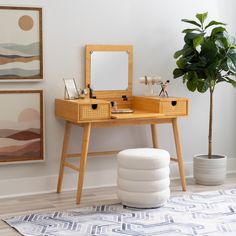 a wooden vanity table with two drawers and a mirror on it in front of a potted plant