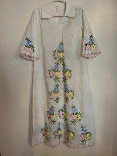 "Vintage 70s handmade Chriffronelle embroidered fabric kaftan. Sheer maxi kaftan with floral embroidery in amazing vintage condition. Beautiful detailing along hem and sleeves with pink embroidered, scalloped border. Floral embroidery in pink, yellow, blue, and green. Dress features 3/4 length bell sleeves, v-neck, collar in front and back with zip and hook and eye closure. Material listed as chiffronelle polyester and pima cotton. Size not listed, as dress is handmade, but would fit up to a siz Spring Cotton Kaftan With Floral Embroidery, Spring V-neck Kaftan With Chikankari Embroidery, Spring Folk Style Embroidered Kaftan, Embroidered Folk Style Kaftan For Spring, Traditional Floral Print Spring Kaftan, Traditional Spring Floral Print Kaftan, Spring Vintage Dress With Embroidered Hem, Traditional Embroidered Hem Kaftan For Spring, Long Kaftan With Multicolor Floral Embroidery