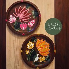 two wooden plates with painted designs on them sitting on top of a wood table next to each other