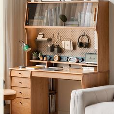 a wooden desk topped with lots of books and office supplies next to a white chair