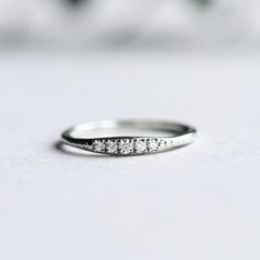 a white gold wedding band with five diamonds on the side, sitting on a table