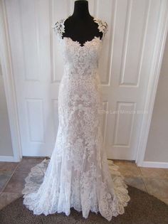 a white wedding dress on display in front of a door with a black mannequin