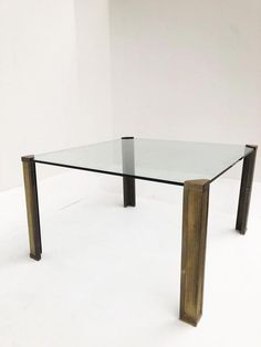 a glass table with metal legs on a white floor