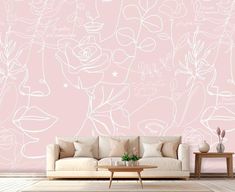 a living room with pink walls and white drawings on it's wall, along with a coffee table