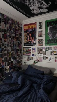 an unmade bed in a room with posters on the wall