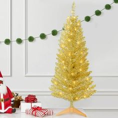 a christmas tree with presents under it and a santa clause figure next to it on a table