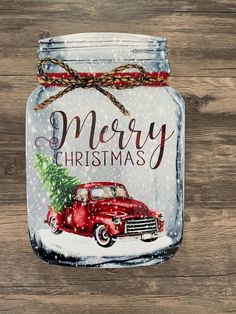 a mason jar with a red truck and christmas tree painted on the front, hanging from a wooden wall