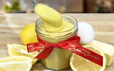 a jar filled with lemon custard next to sliced lemons