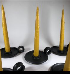 four yellow candles sitting on top of each other with black holders in front of them