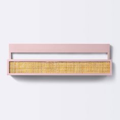 a pink and yellow wall hanging on the side of a white wall next to a wooden shelf