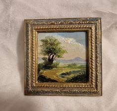 a painting hanging on the wall next to a white bed sheet with a tree and mountains in the background